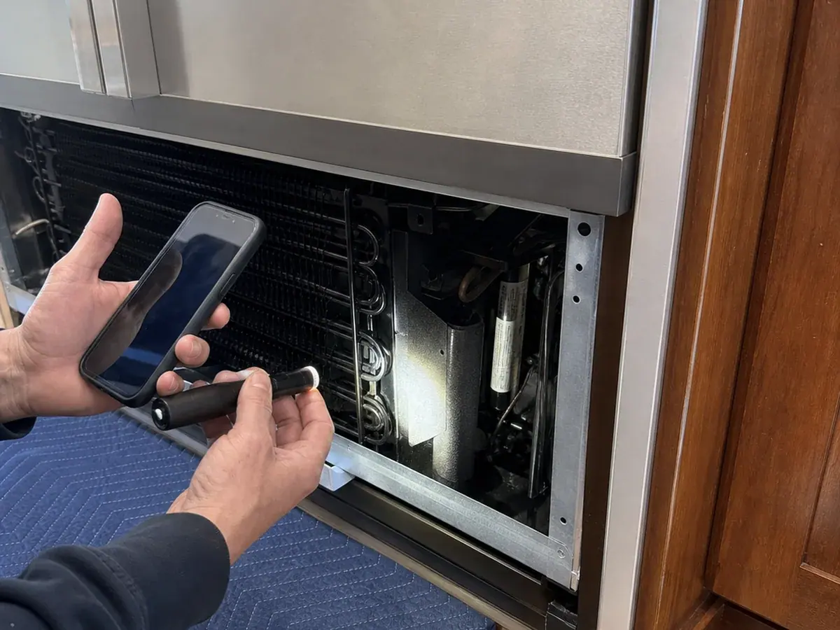 Technician photographing the model and serial tag area inside a Novato built-in refrigerator