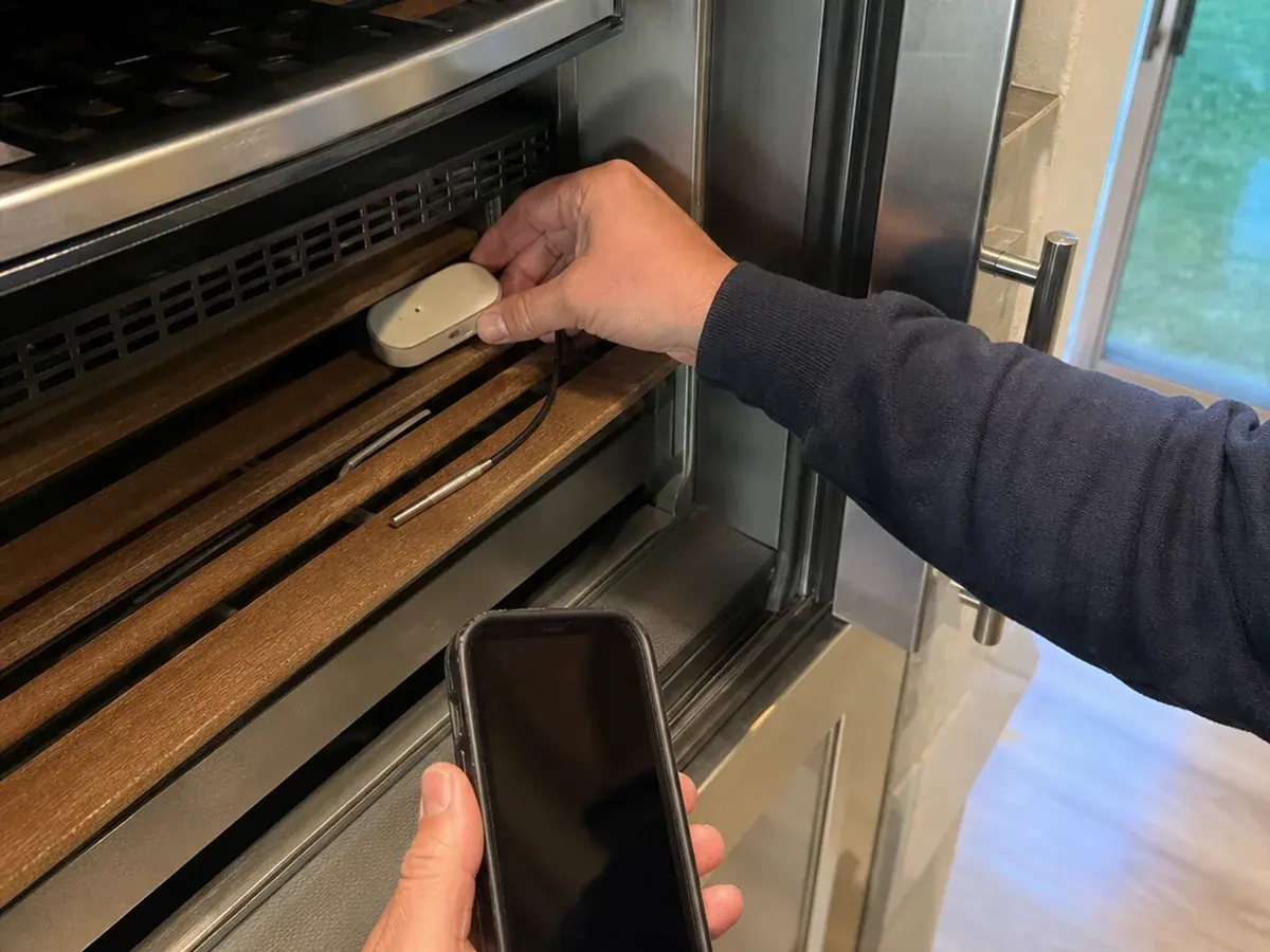 Technician placing a temperature data logger inside a Novato wine storage cabinet